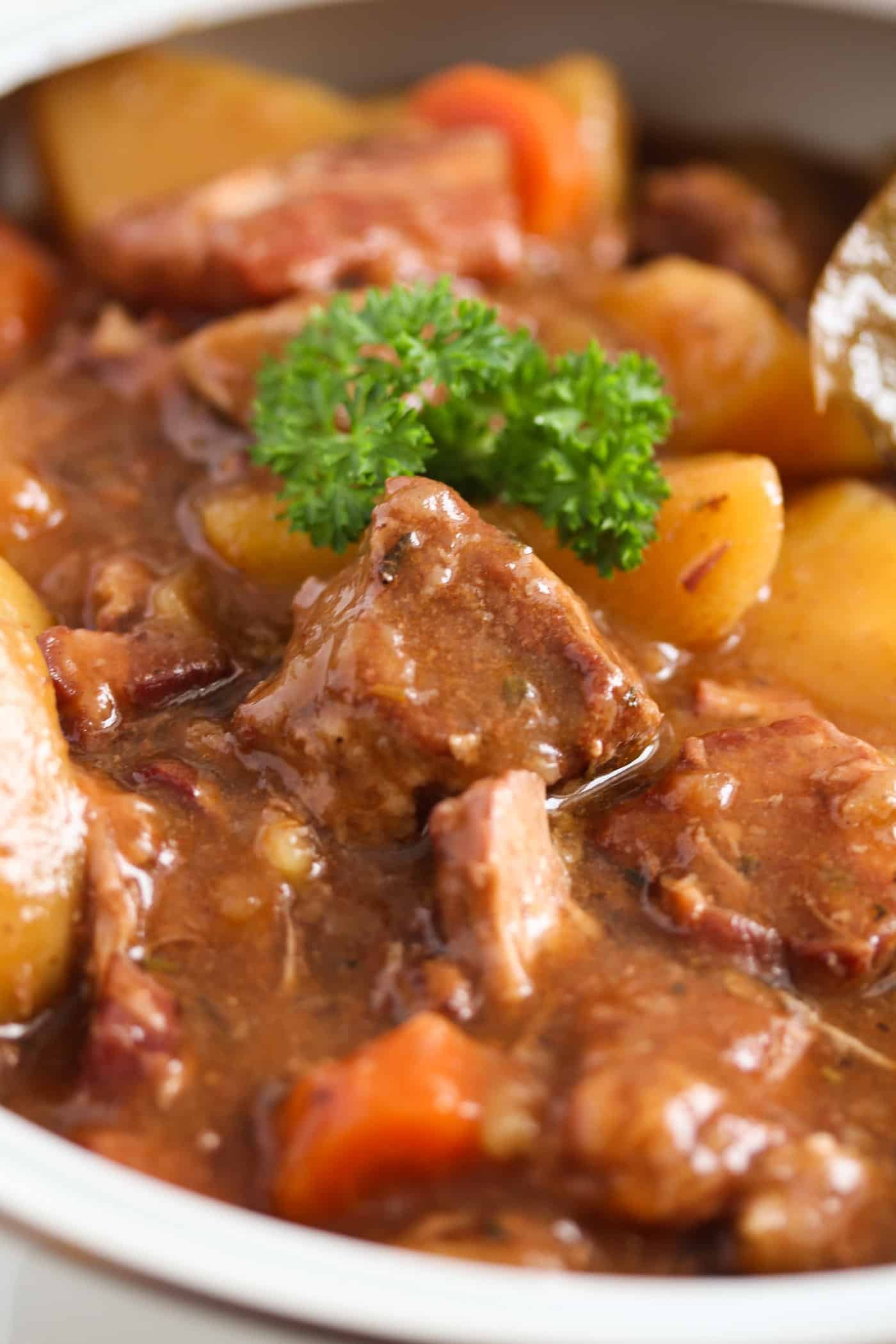 close up pieces of glossy meat and potatoes in a pot.