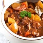 meat, potatoes and carrots with gravy in a pot.