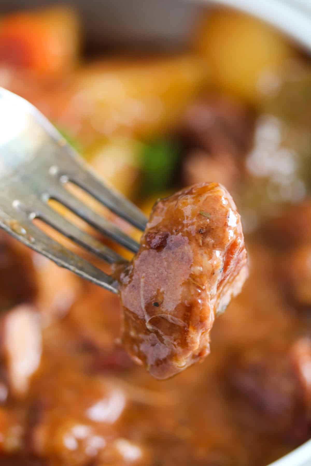 fork holding a piece of tender lamb.