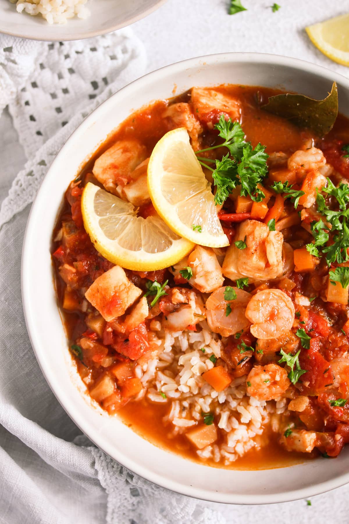 fish stew with shrimp served with rice and lemon slices in a bowl.