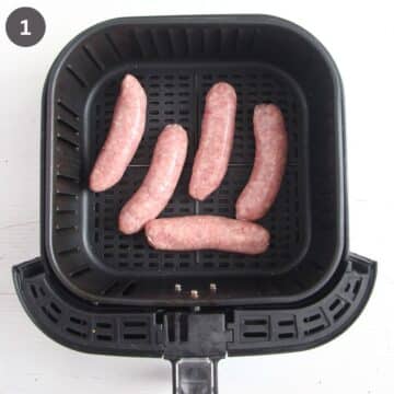 four raw brats in the air fryer basket.
