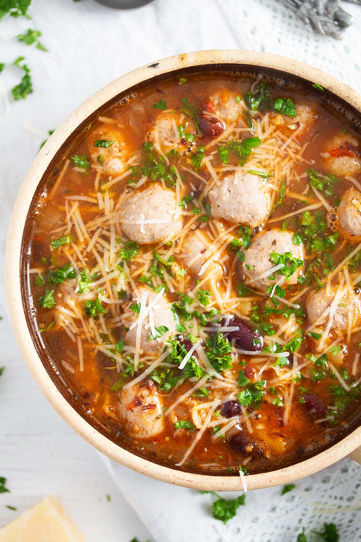 a bowl full of soup with brat meatballs and beans.