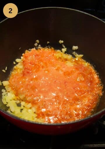 adding tomato paste to sauteed onions in a pan.