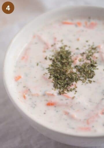 yogurt and carrot sauce sprinkled with herbs in a bowl.