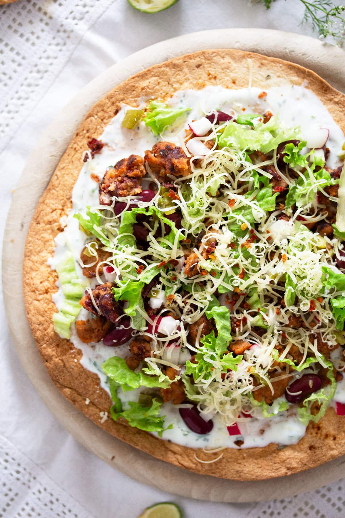 one large chorizo tostada topped with beans, cilantro and cheese.