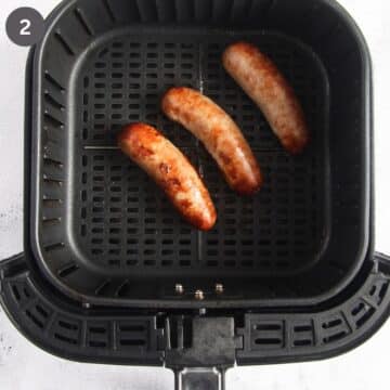 three golden brown air fried brats in the air fryer basket.