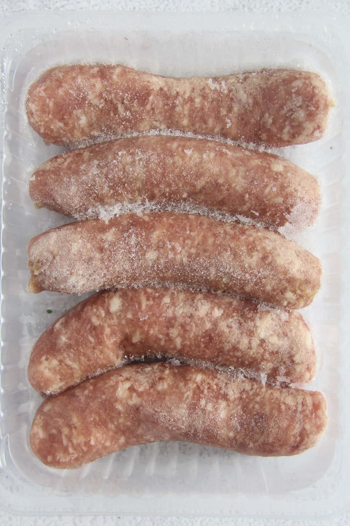 five frozen brats in a plastic container.
