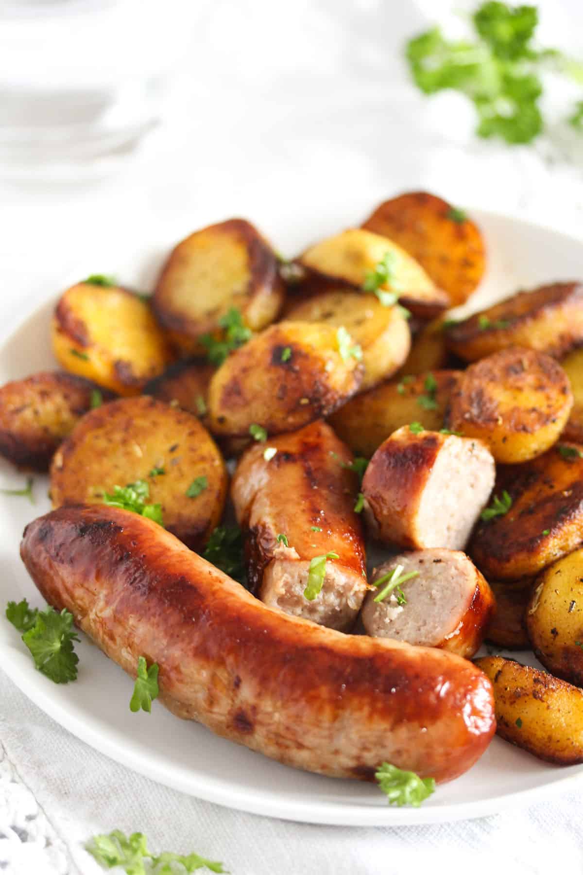 plate with cooked sausages and roasted potatoes.