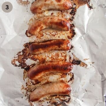 cooked brats on a foil lined baking sheet.