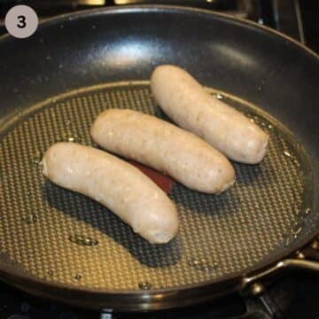 three uncooked sausages in a friyng pan.