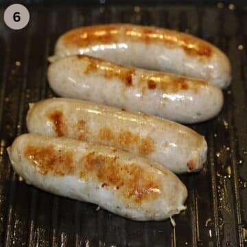 four browned sausages cooked in a grill pan.