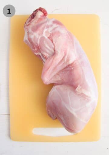 one whole uncooked rabbit on a cutting board.