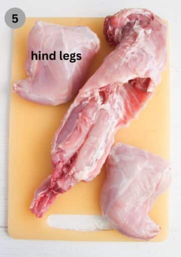 cut up rabbit parts on a cutting board.