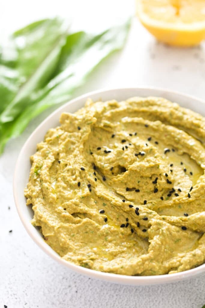 wild garlic hummus sprinkled with seeds in a bowl.