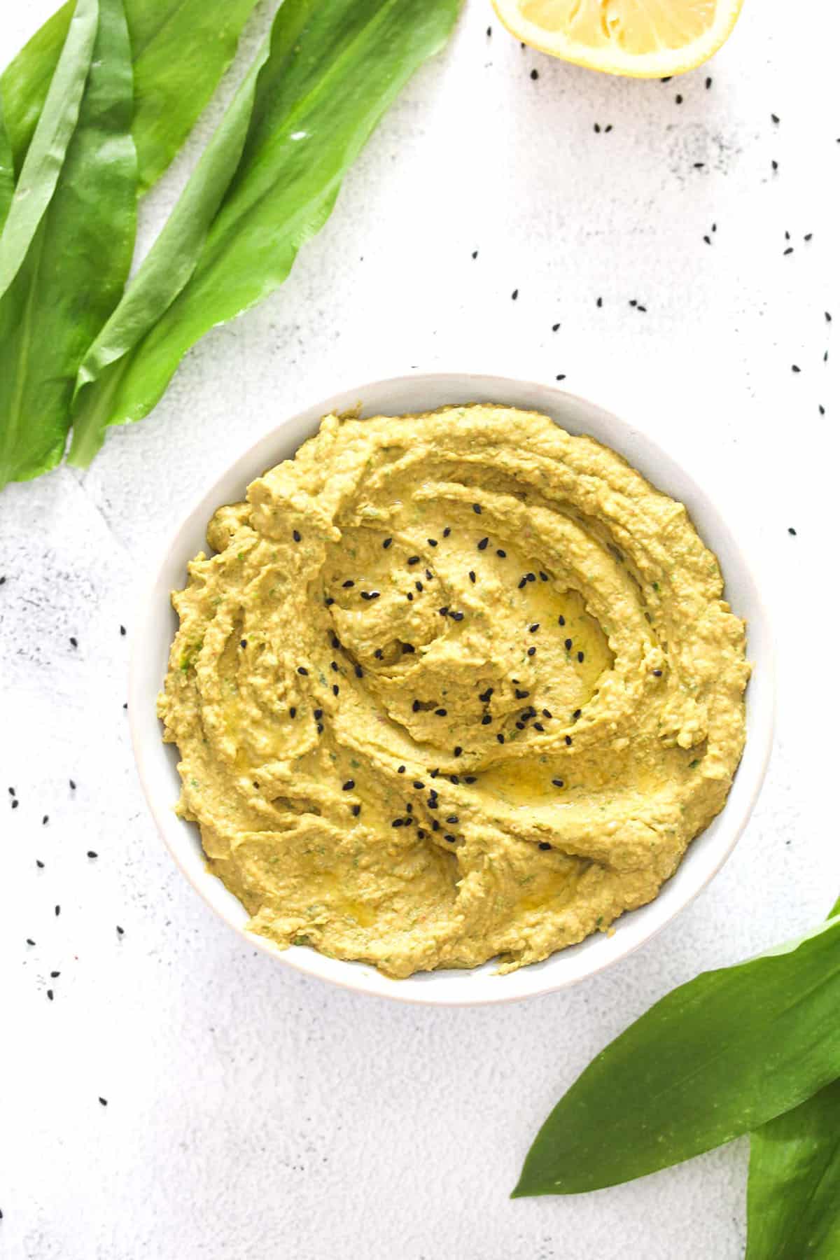 bowl of wild garlic hummus and wild garlic leaves.
