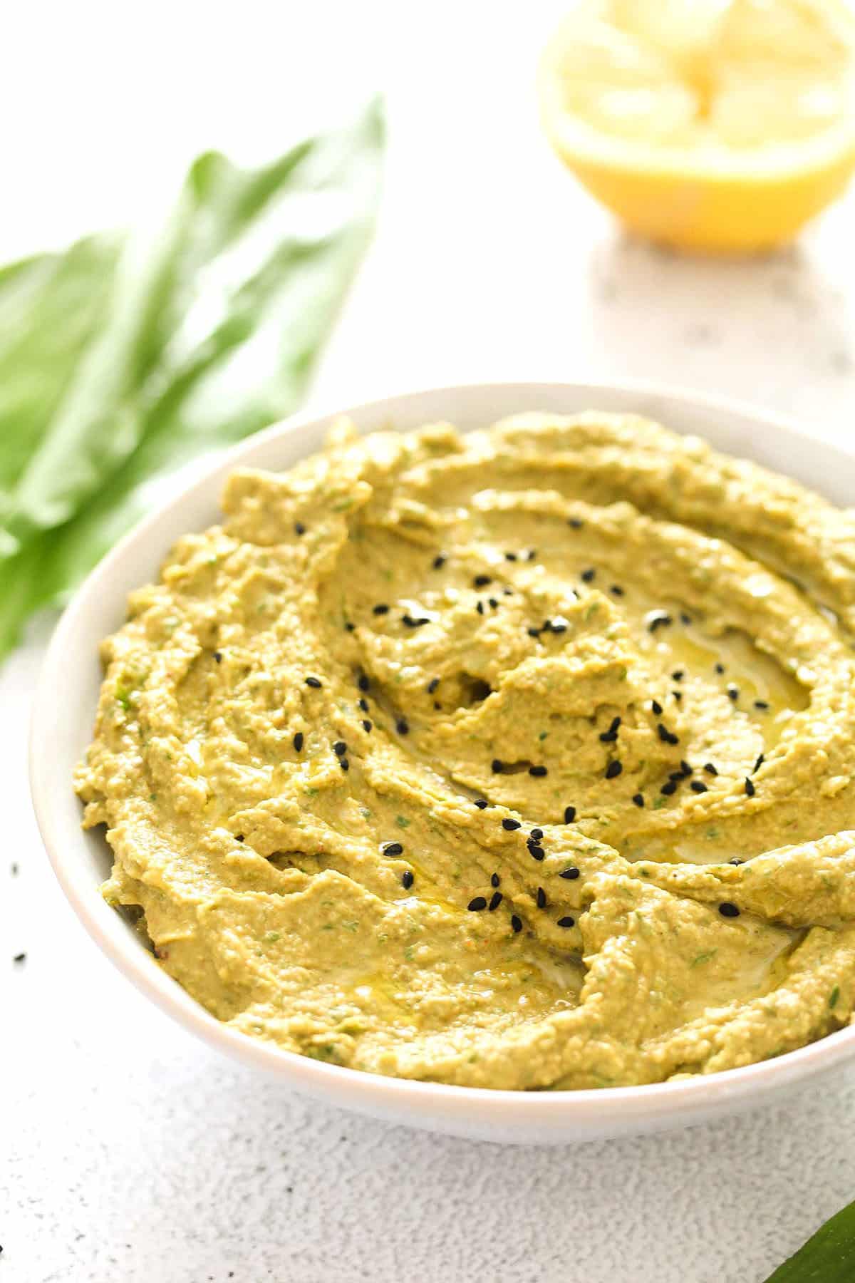 wild garlic hummus in a bowl and a lemon behind.