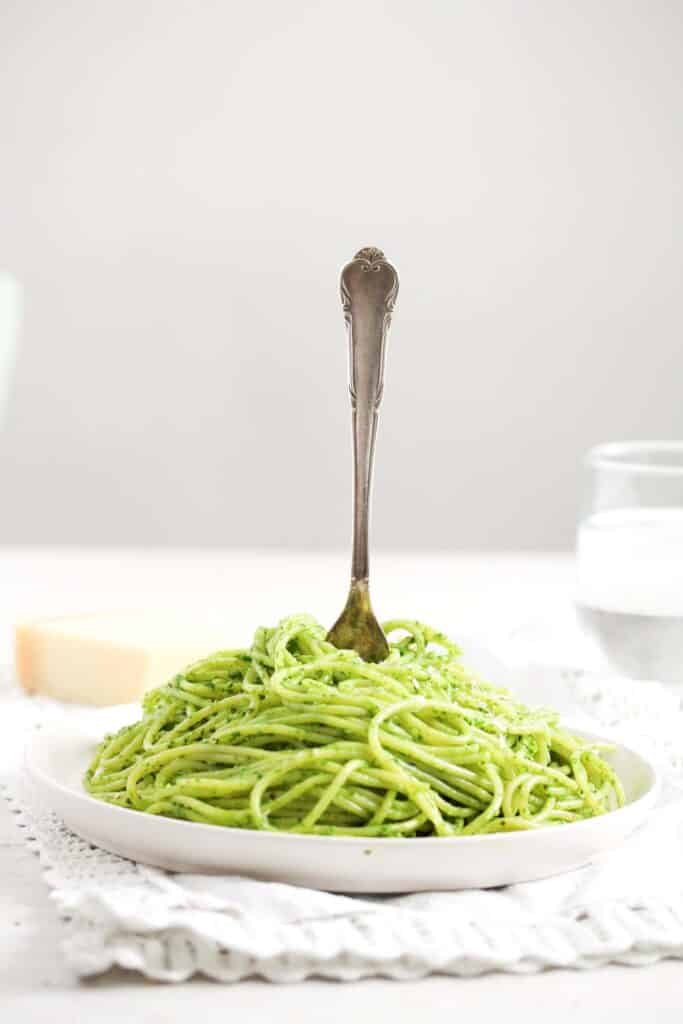 plate of pesto pasta with a fork stuck into it.
