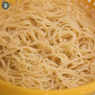 cooked spaghetti tangled in a sieve.