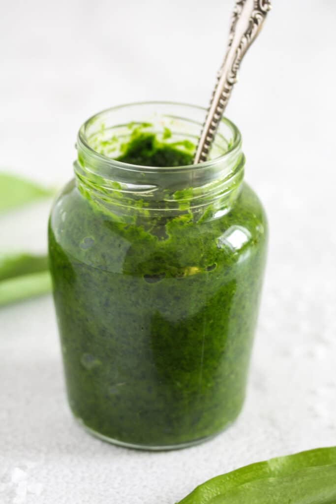 wild garlic paste in a small jar with a spoon in it.