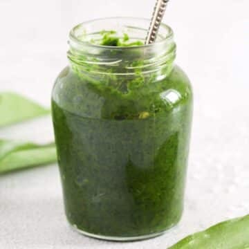 preserved wild garlic with salt in a small jar with a spoon in it.