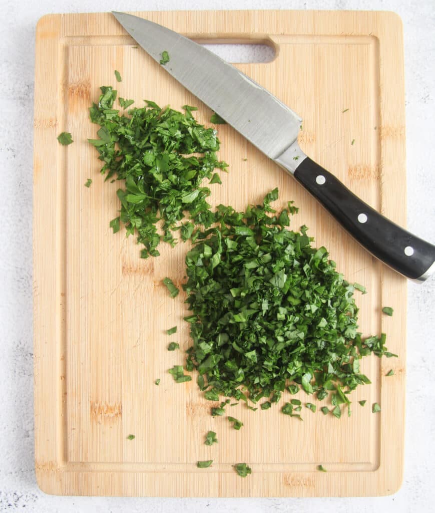 chopping herbs on a wooden board.