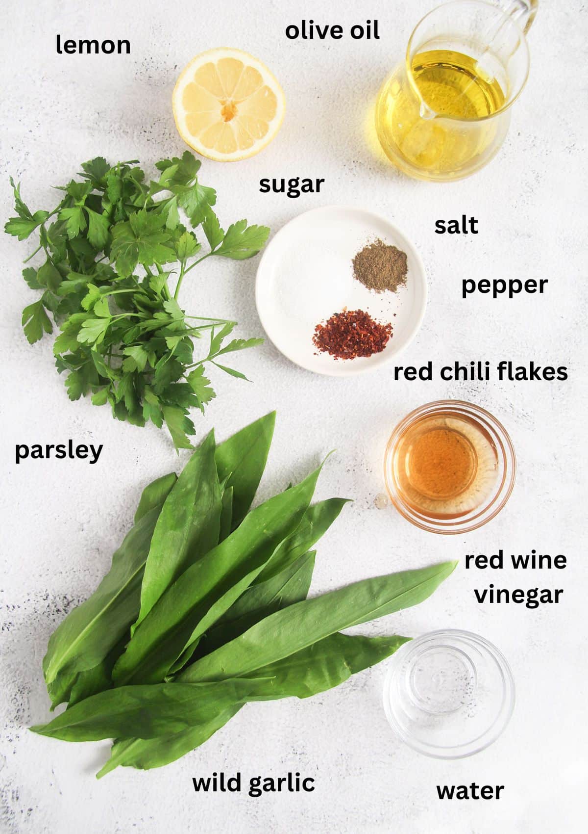 labeled ingredients for making sauce with wild garlic, parsley, olive oil, lemon, vinegar, and seasoning.