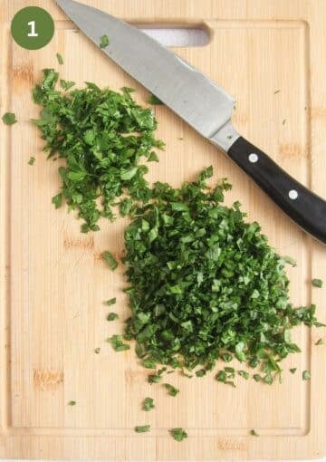 finely chopped wild garlic and parsley on a wooden cutting board and a chef's knife.