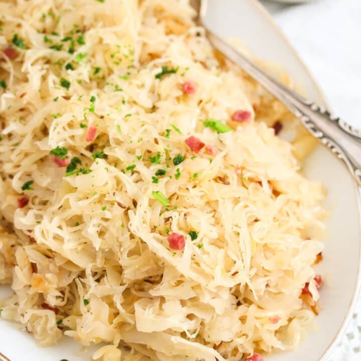 plate with sauerkraut and bacon with mustard bowl beside.