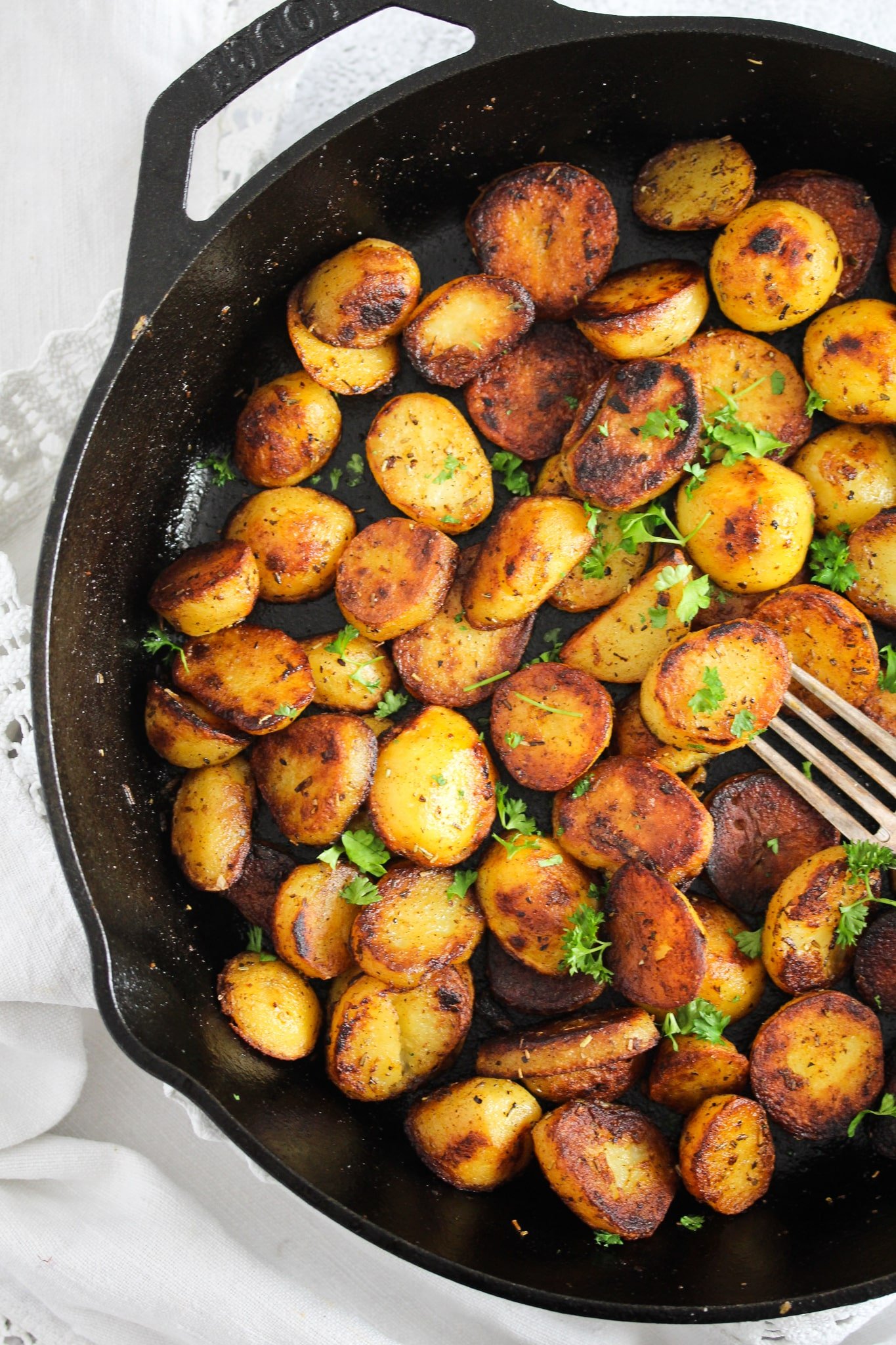 many small potatoes in a heavy-bottomed cast iron pan with a fork.