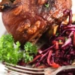 pinterest image of a large pork knuckle on a plate.