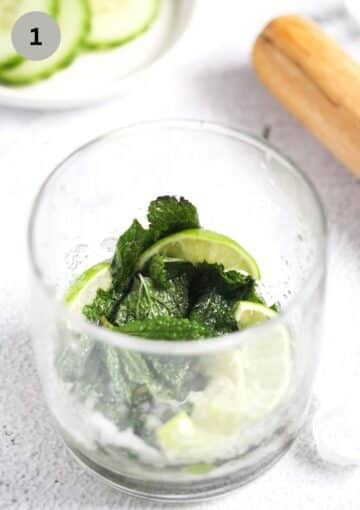 crushed mint, lime slices and sugar to make cocktail in a glass.