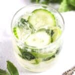 glass of gin mojito with cucumber and lime slices.