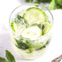 glass of gin mojito with cucumber and lime slices.