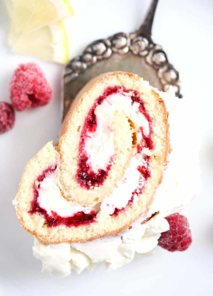 overhead view of a slice of raspberry lemon roll on a cake lifter.