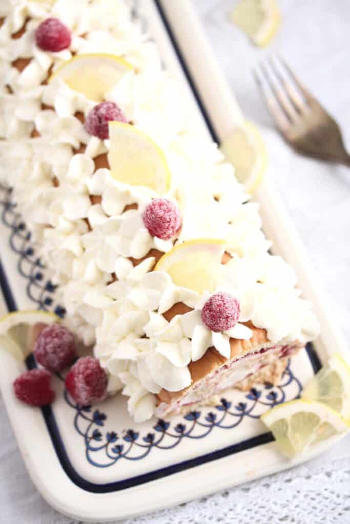 rolled cake with berry lemon filling on a platter.