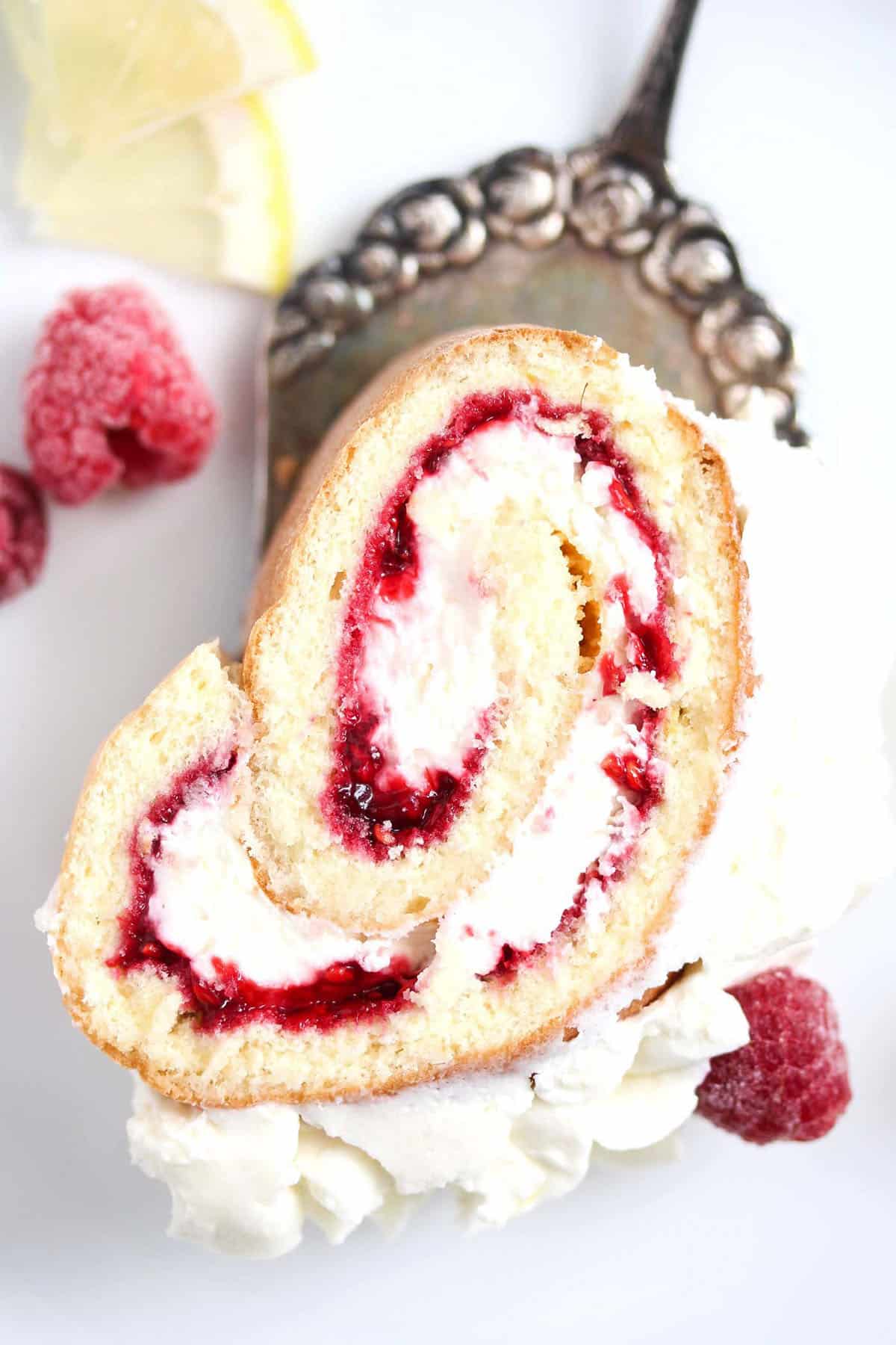 one slice of raspberry roulade on a cake lifter showing the filling.