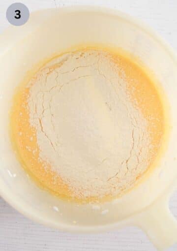 adding flour to beaten egg yolks and sugar in a bowl.