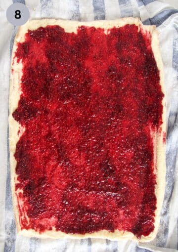 covering a roulade sheet of cake with raspberry filling.