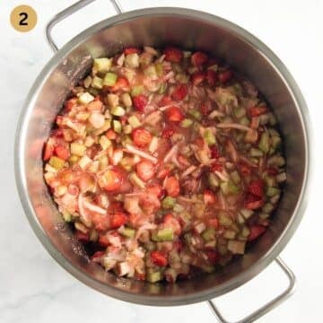 chopped strawberries and rhubarb for making jam in a pot.