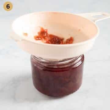 placing jam in a small jar using a jam filler.