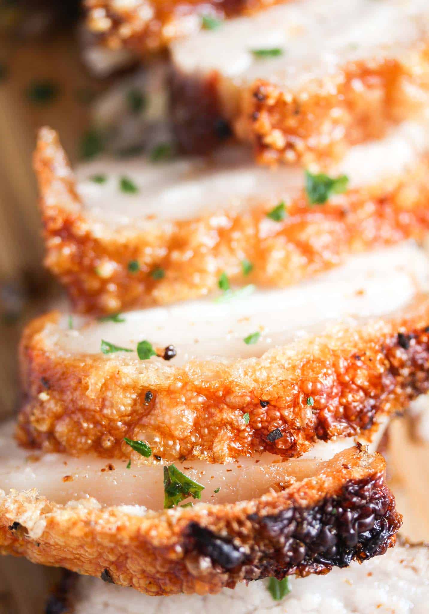 crispy pork with crackling sliced on a wooden board and sprinkled with parsley.