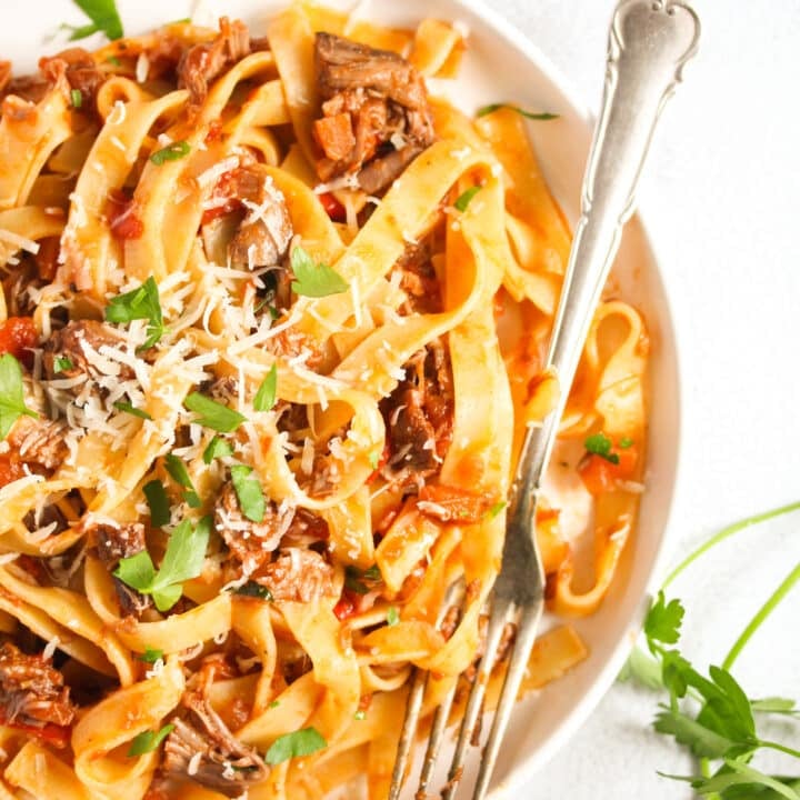 close up pappardelle with lamb ragu on a plate with a fork.