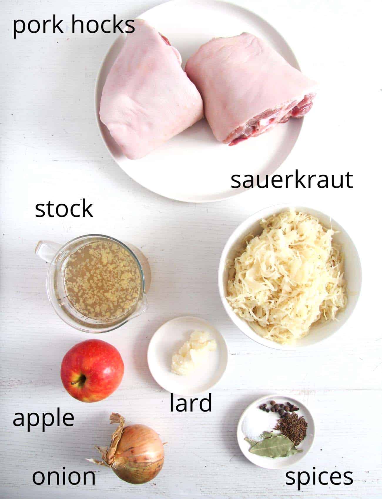 ingredients for cooking knuckles. two pork hocks, sauerkraut, stock, apple, lard, spices, onion.