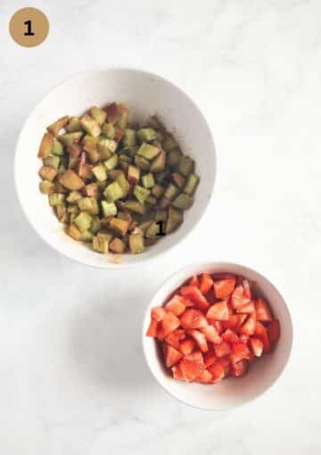 one bowl with chopped strawberries and one bowl with chopped rhubarb mixed with cinnamon.