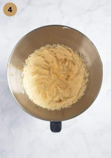 adding egg yolks to beaten butter and sugar in a bowl to make cake.