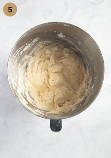 adding flour and yogurt to cake batter in a bowl.