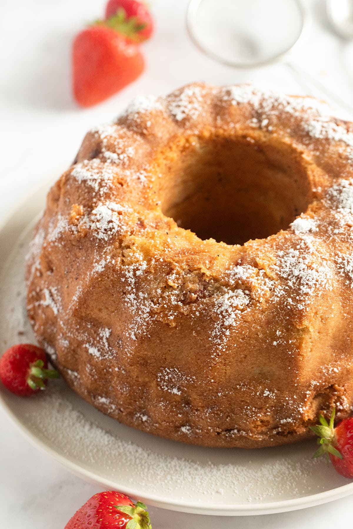one bundt cake with rhubarb and strawberries and some fresh strawberries on a platter.