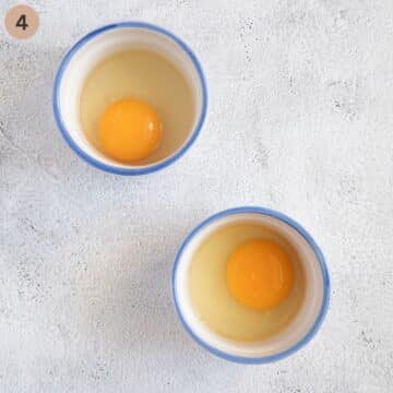 two raw eggs in small bowls for poaching.