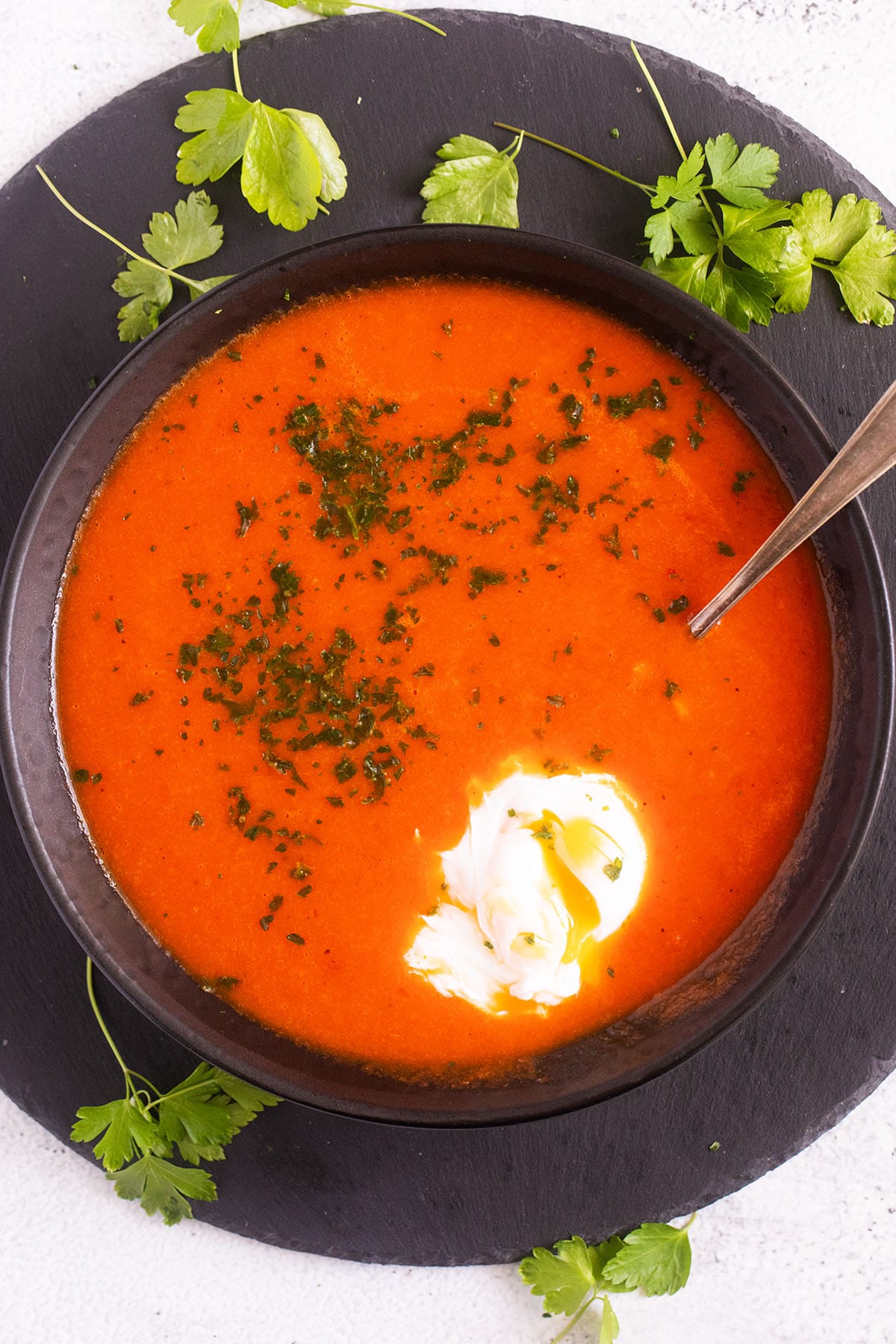 a bowl of tomato soup with a poached egg inside and cilantro.