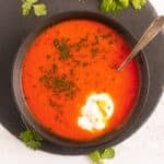 tomato soup with egg in a bowl on a round cutting board.